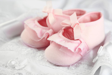 Fototapeta na wymiar Pink baby boots on cloth close-up