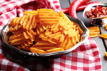 Delicious potato chips on plate on wooden table close-up