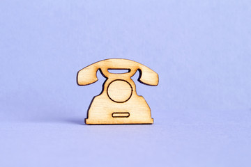 Wooden icon of telephone on purple background