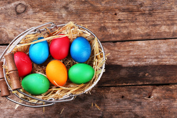 Easter eggs in basket on vintage wooden planks background