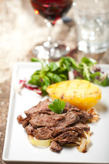Scheiben vom Steak auf einen Teller mit Salat