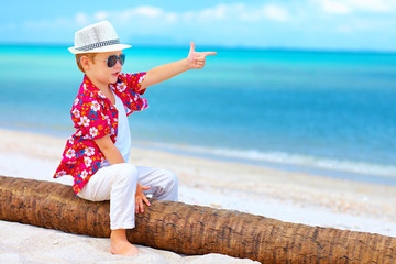 cute boy playing a gangster on summer beach