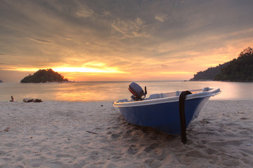 Blue fishing boat at sunset on the beach