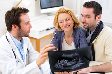 Fototapeta premium Doctor shows an ultrasound to a young happy couple