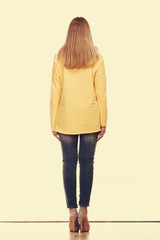 woman in denim pants yellow blouse back view