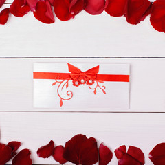 Greeting card with red ribbon, rose petals.