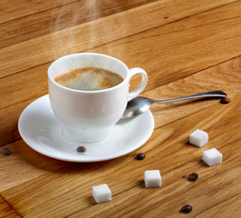 Hot fresh coffee in a white cup with sugar on wooden table
