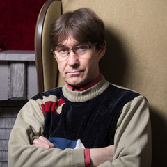 Serious man in sweater sitting on the couch