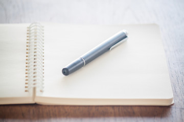 Blank notebook with pen on wooden table