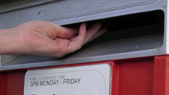 Slow motion of person hand posting a letter in a mail letter box