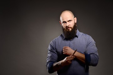 Fototapeta na wymiar Man with a beard holding a pair of scissors