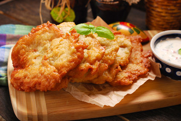 potato cakes lying on wooden board with bowl of  vegetable and m