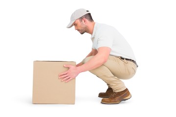 Delivery man crouching while picking cardboard box