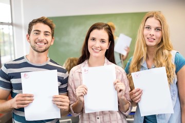 Happy students holding papers in class