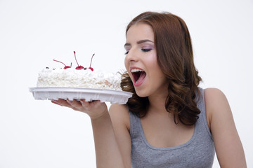 Portrait of a young woman bitting cake over gray background