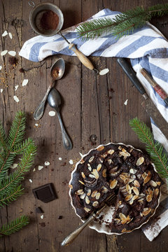 dark chocolate and almonds cake on table with pine branches