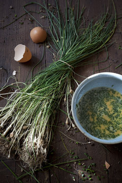 preparing an omelette with fresh beaten eggs and wild chives