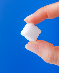 White sugar cube held between fingers
