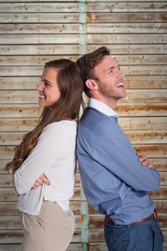 Composite image of happy young couple standing back to back