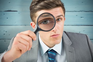 Fototapeta na wymiar Composite image of businessman looking through magnifying glass