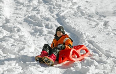 Child plays with sled in the snow