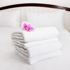Fototapeta na wymiar white towels and pink orchid on the bed