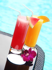 glasses of juice with a card by the swimming pool