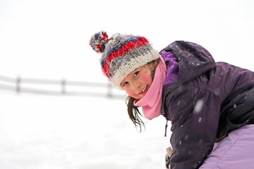 Fototapeta na wymiar pretty little girl with wool beret playing on snow in the winter