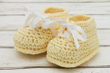 Pale Yellow Baby Booties on wood background