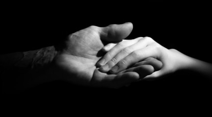 Hand of old and young man in a low key. black and white