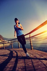 Abwaschbare Fototapete Joggen junge Fitness-Frau, die auf der Promenade am Meer läuft