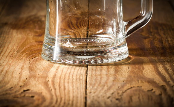 The lower part of the empty beer glass on a wooden table