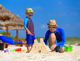 father and son building sand castle on the beach