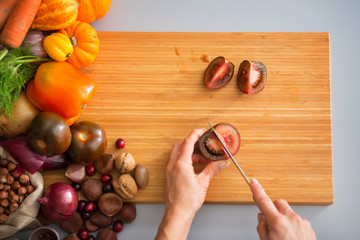 Closeup on young housewife cutting cherokee purple tomato