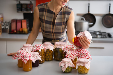 Closeup on young housewife checking jars 
