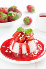 Vanilla panna cotta with strawberry sauce and nuts, vertical