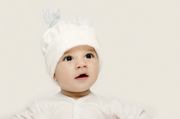 Innocent baby wearing a white bunny hat looking adorable.