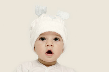 Innocent baby wearing a white bunny hat looking adorable.
