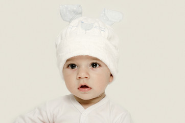 Innocent baby wearing a white bunny hat looking adorable.