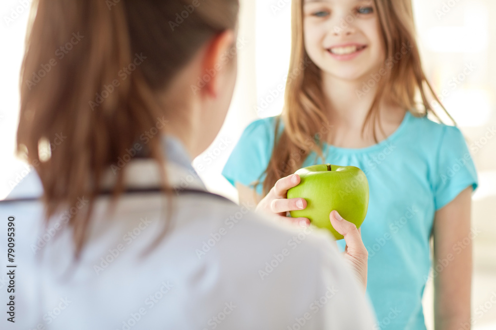 Wall mural close up of doctor giving apple to happy girl