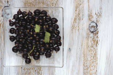 Frozen black currant on white painted wooden background.