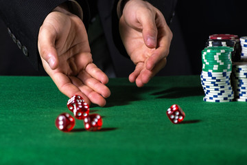 Male hand rolling five dice on green felt