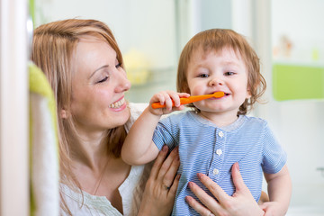 mother and little son brushing teeth in bathroom