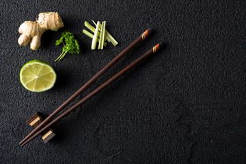Chopsticks and food ingredients on black stone table top view
