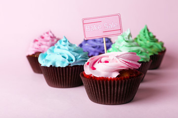 Delicious cupcakes with inscription on color background