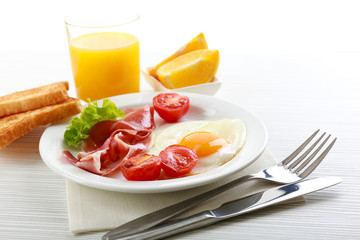 Bacon and eggs on color wooden table background