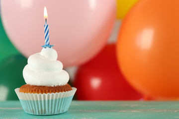 Delicious birthday cupcake on table on bright background