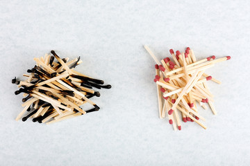 Piles of burnt and whole matches on light background