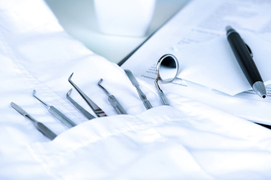 Dentist tools in pocket of medical robe on table close up