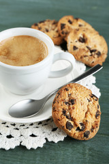 Cup of coffee and tasty cookie on color wooden background
